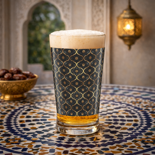 Midnight Marrakech pint beer glass with with a black and gold design, and filled with beer sitting on a Moroccan mosaic table