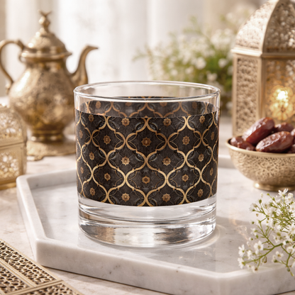 Midnight Marrakech rocks glass with a black and gold design sitting on a marble tray with teapots and dates in the background