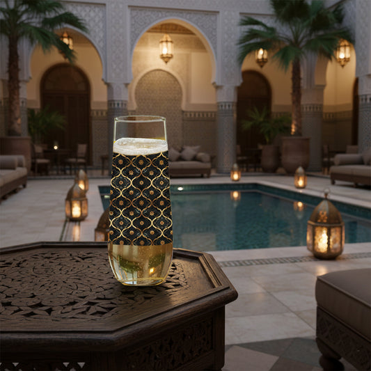 Midnight Marrakech stemless champagne glass with black and gold pattern on a table by a poolside in an elegant outdoor setting.