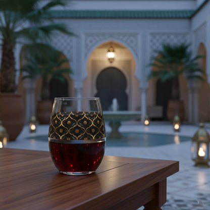 Midnight Marrakech stemless wine glass with a black and gold design, sitting on a wooden table in an outdoor setting with Moroccan architectural elements and lanterns.