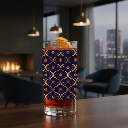 Midnight Marrakech highball glass with a violet and gold design on a wood table with a fireplace and city view in the background